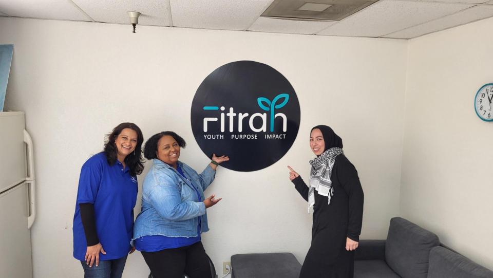 volunteers posing and pointing to nonprofit logo, Fitrah