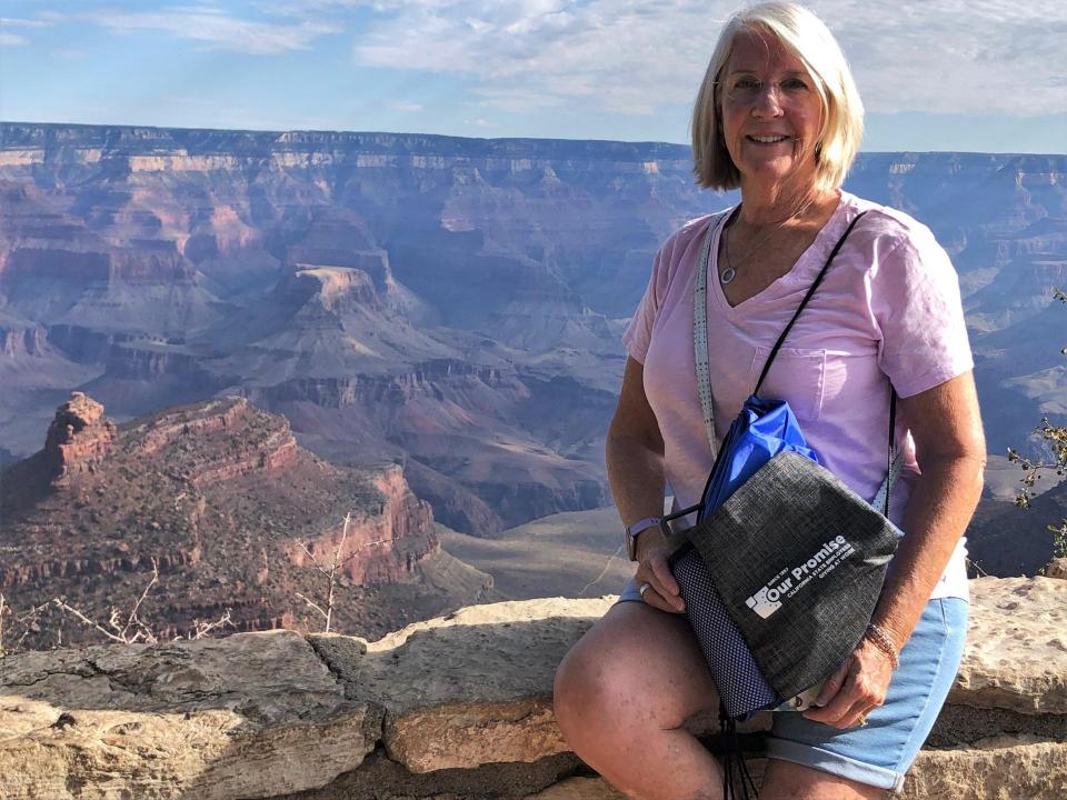 Kathy at the Grand Canyon smiling and holding an Our Promise bag