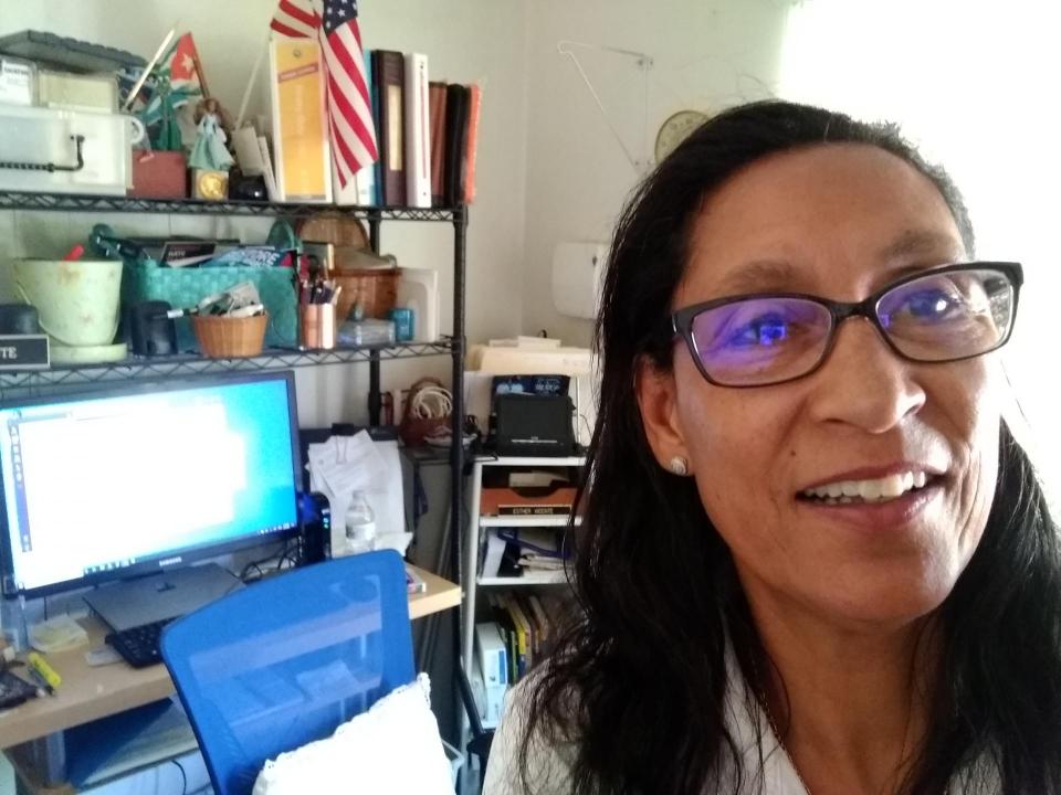 Selfie Photo of a Latina smiling, wearing glasses at her computer.