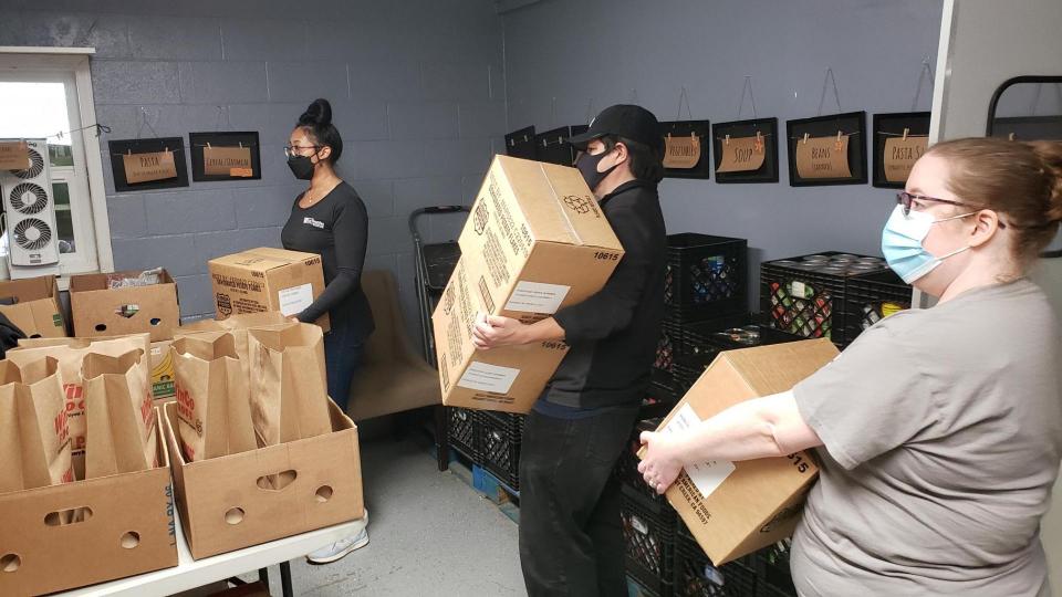 A group of people in a room with boxes of food.